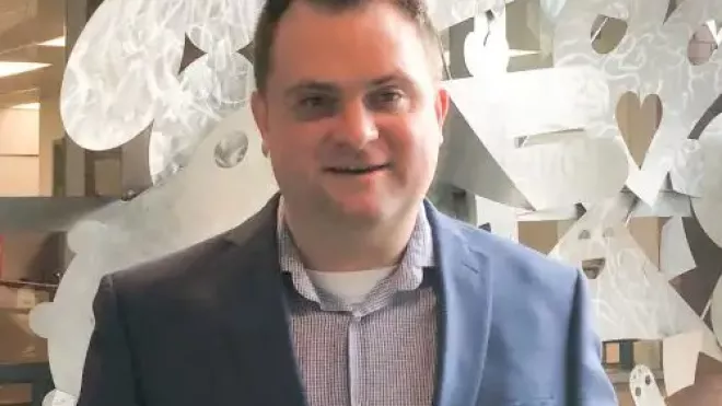 Jamie smiling in front of a sculptural background