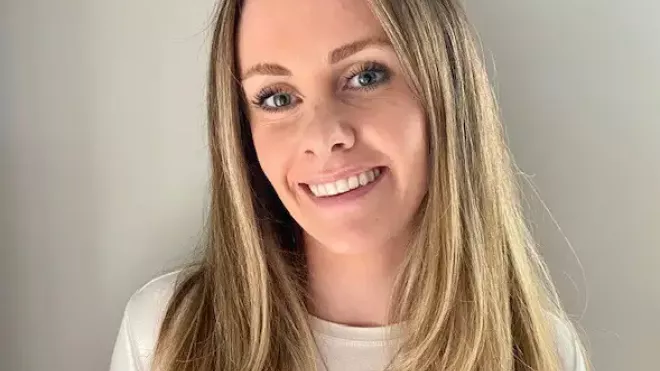 Megan smiling in front of a neutral background