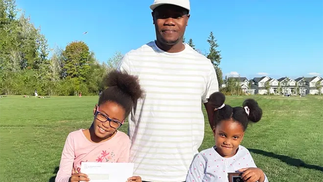 Aaliyah with her dad and sister outside holding the 2021 Hero of Ability award